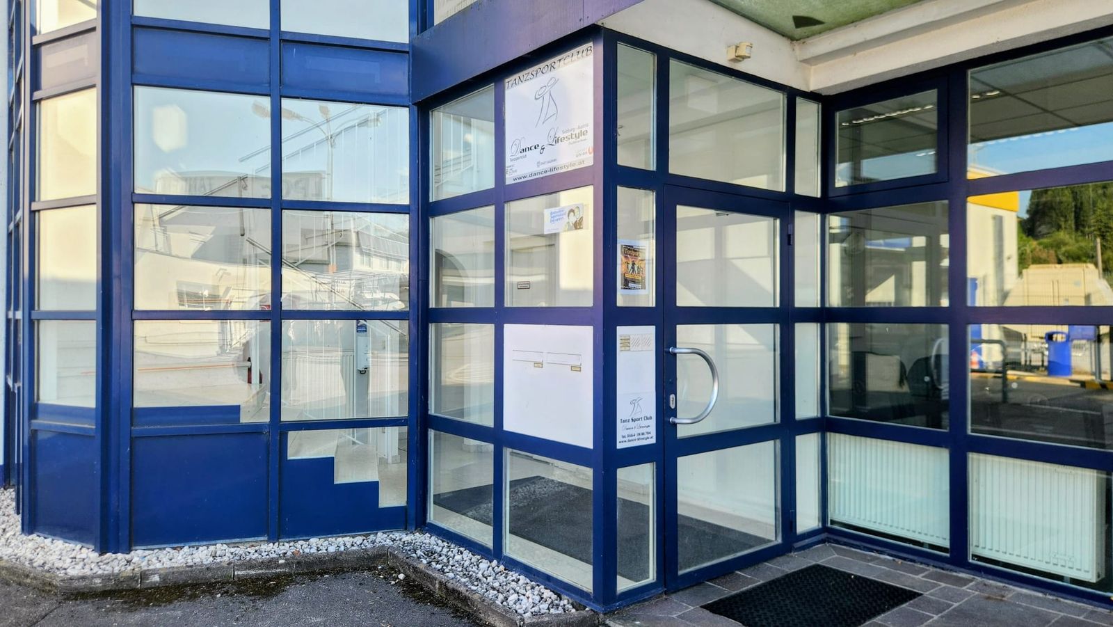 Eingang des Studios: blau gerahmte Glastür mit dem Schild „Tanzsportclub Dance & Lifestyle“